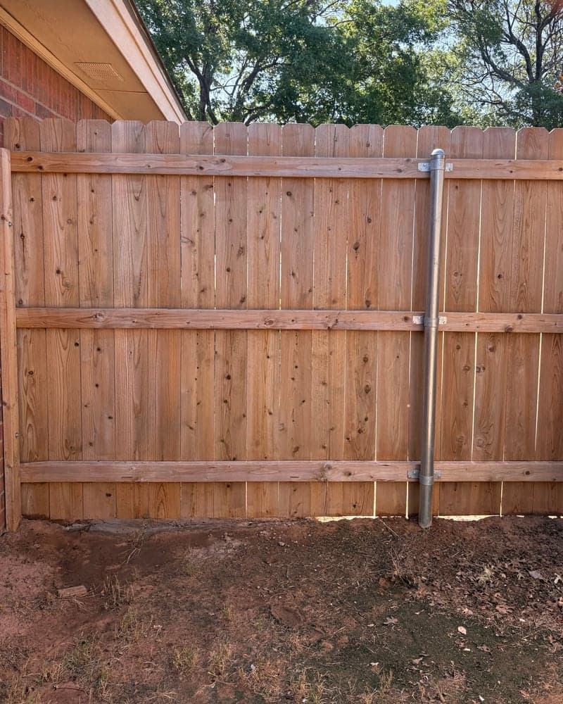 Unstained wood gate beside a brick house, before staining