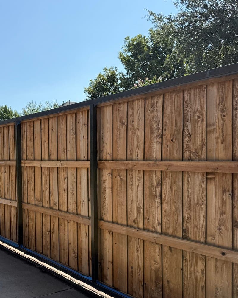 Unstained wood privacy fence with a black metal frame, before staining